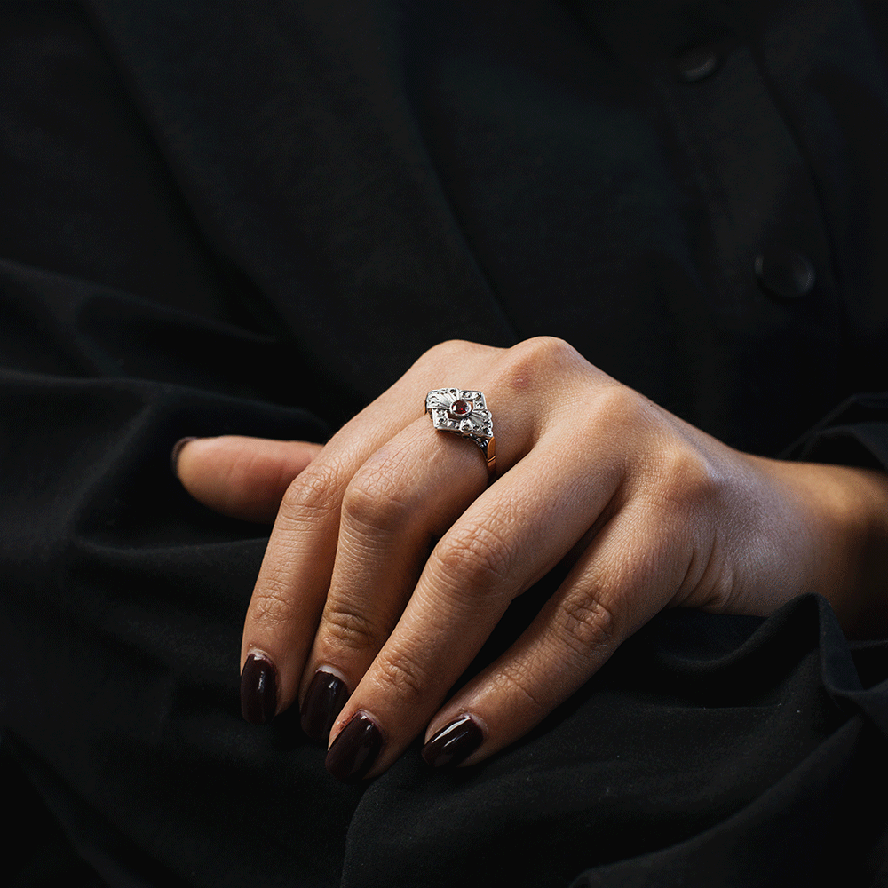 Anillo Victoria en plata y oro de 18K, fotografiado en una mano inclinada para mostrar el relieve de la montura y el rubí central.