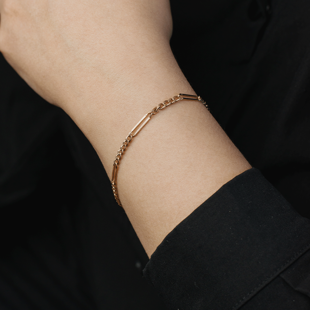 Pulsera diseño Cartier en oro de 18k puesta en la muñeca, con eslabones cortos y alargados sobre fondo negro