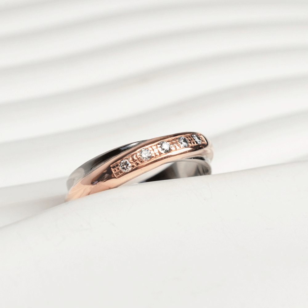 Detalle de los cinco brillantes y las bandas entrelazadas del anillo Aurore en oro blanco y rosado de 18k