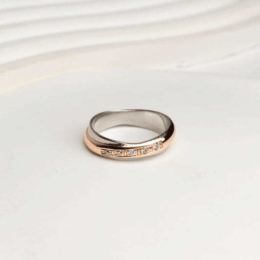 Anillo Aurore en oro blanco y rosado de 18k, con bandas entrelazadas y cinco brillantes, sobre fondo blanco.