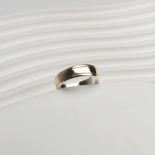 Vista inclinada del anillo Éternité en plata y oro 18K, con franja central de oro y bordes de plata pulida.