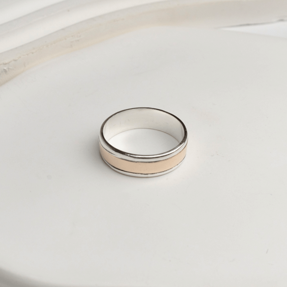 Anillo Éternité en plata y oro 18K sobre fondo blanco, con detalle de la franja central de oro y el interior de plata.