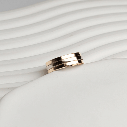 Vista inclinada del anillo Alliance en oro blanco y oro rosado de 18K, con bandas pulidas sobre fondo blanco