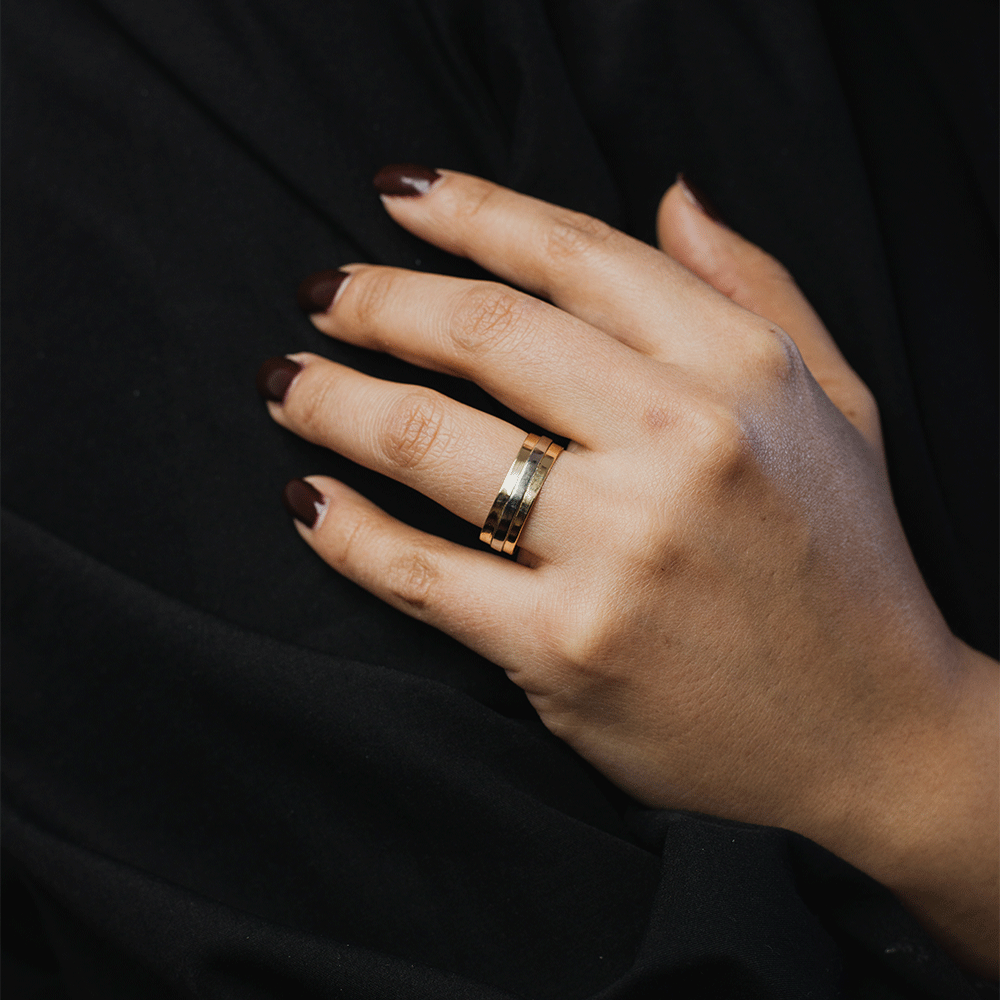 Anillo Alliance en oro blanco y oro rosado de 18K, puesto en el dedo anular de una mano sobre fondo negro