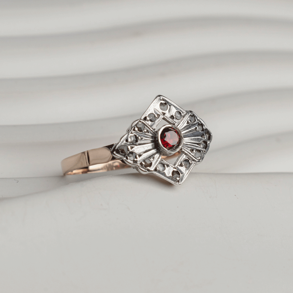Anillo Victoria en plata y oro de 18K, con rubí central y diamantes en una montura calada de diseño geométrico