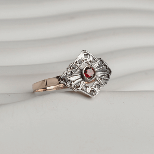 Anillo Victoria en plata y oro de 18K, con rubí central y diamantes en una montura calada de diseño geométrico