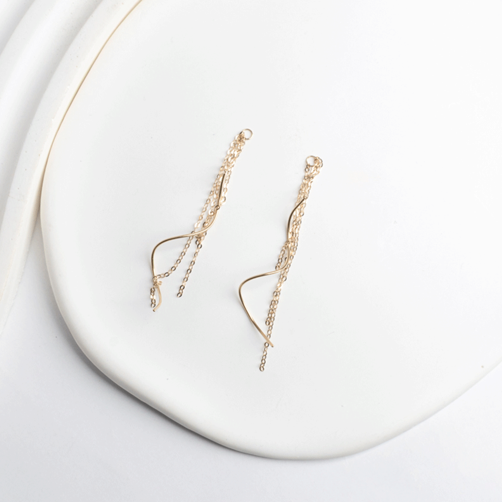 Detalle de los aros Juliette en oro de 18K, con cadenas de distintos largos y piezas curvas sobre fondo blanco