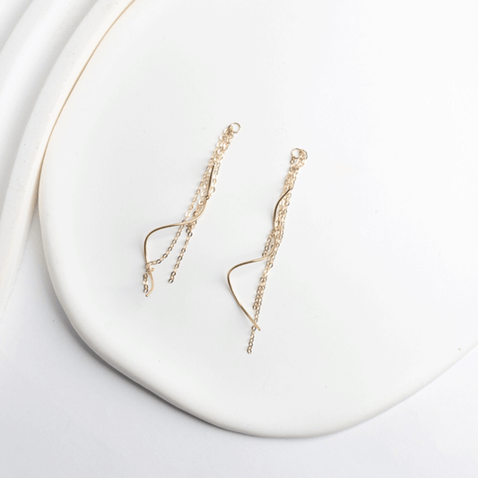 Detalle de los aros Juliette en oro de 18K, con cadenas de distintos largos y piezas curvas sobre fondo blanco