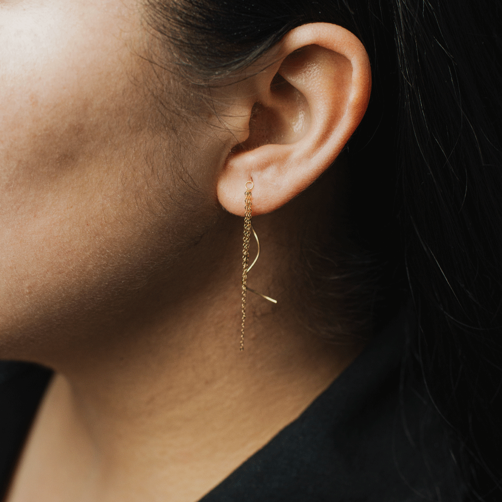 Aro Juliette en oro de 18K puesto en la oreja, con cadenas en cascada y un detalle curvo que cuelga junto al rostro.