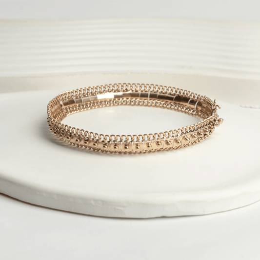 Pulsera Amaya en oro de 18k sobre una base clara, con detalles centrales en relieve y bordes de eslabones