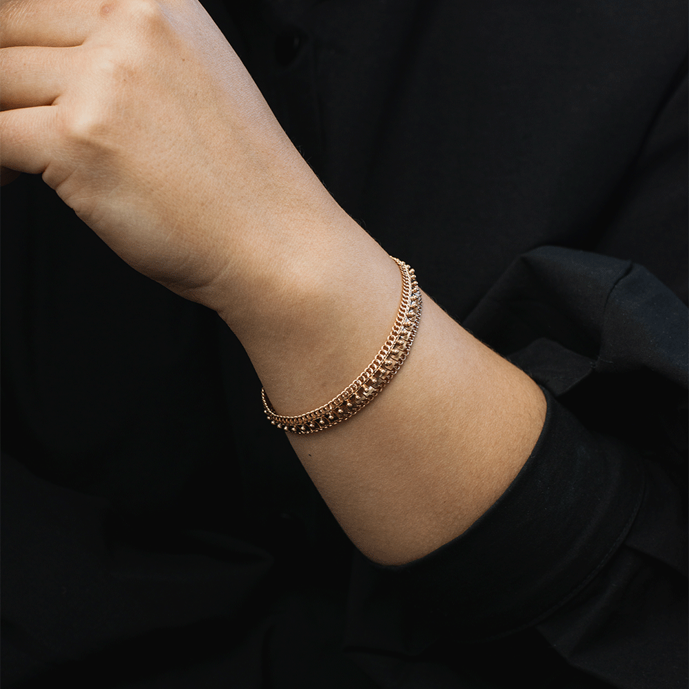 Pulsera Amaya en oro de 18k puesta en la muñeca, mostrando su diseño ancho con detalles en relieve y bordes de eslabones