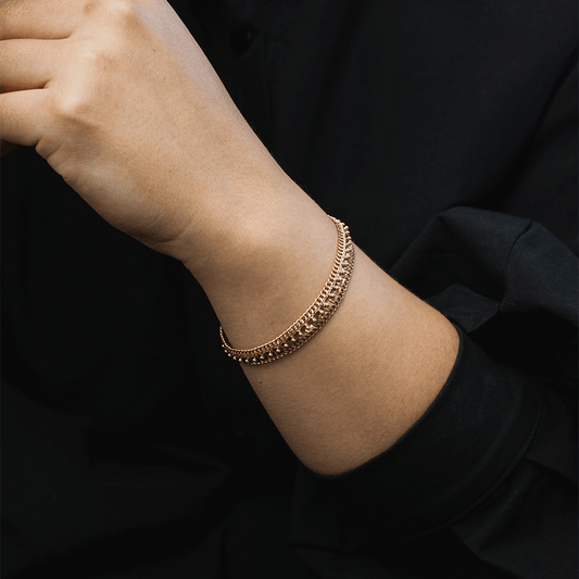 Pulsera Amaya en oro de 18k puesta en la muñeca, mostrando su diseño ancho con detalles en relieve y bordes de eslabones