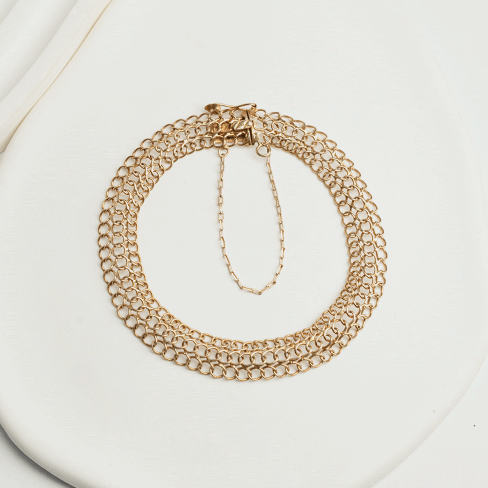 Pulsera Belle en oro de 18k sobre fondo claro, con varias hileras de eslabones redondos y cadena de seguridad visible