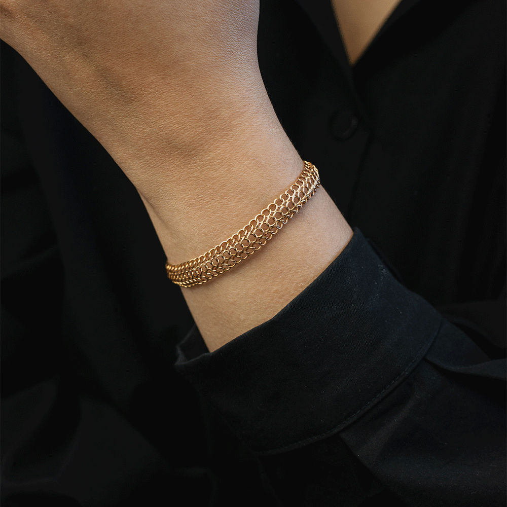 Pulsera Belle en oro de 18k puesta en la muñeca, mostrando sus hileras de eslabones redondos sobre ropa negra