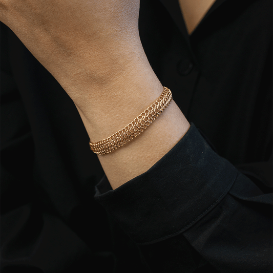 Pulsera Belle en oro de 18k puesta en la muñeca, mostrando sus hileras de eslabones redondos sobre ropa negra